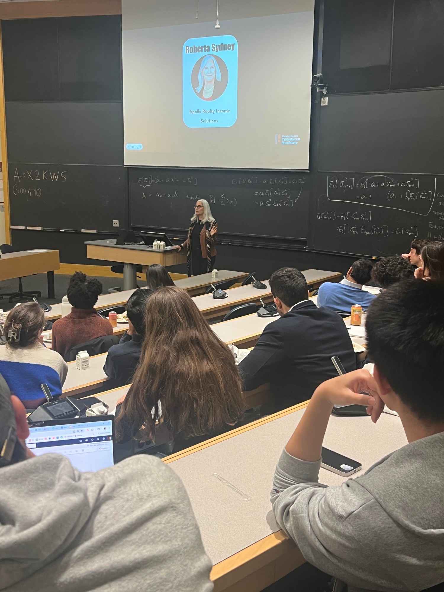 A guest speaker addressing students in a university classroom